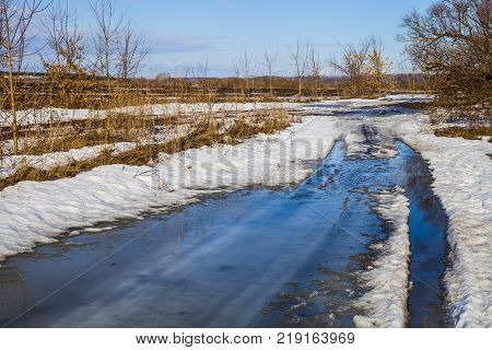 Beautiful spring landscape. Country road near the forest and fields in a sunny spring day.Snowbreak.