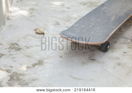 skateboard leaning against white concrete wall and dirty floor