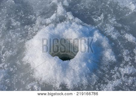 Thick ice of the Gulf of Finland. Fishing hole drilled by a fishing auger