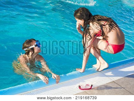 Two happy children playing on the swimming pool at the day time. Concept of friendly family. Two happy children playing on the swimming pool at the day time. Concept of friendly family.