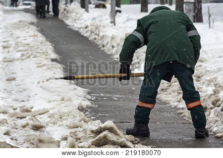 A worker removes snow from the road in the cold winter