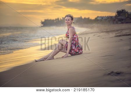 girl in a dress on the seashore during the sunset
