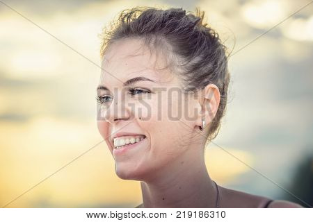 Portrait of beautiful smiling girl on the background of sunset