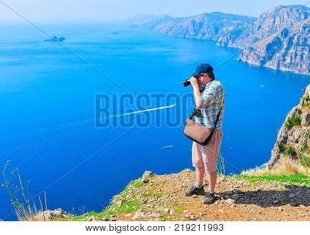 Man taking photos of beautiful scenery at Path of Gods on Tyrrhenian sea Amalfi coast Italy