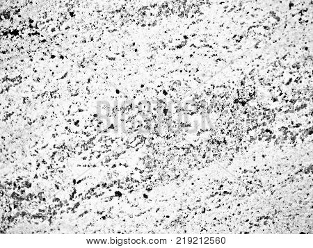 A close-up of a surface of black-and-white treated granite rock plate. A fragment of a stone wall decoration. Texture of grey granite facing material.