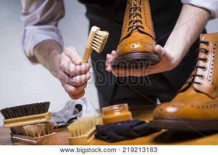 Footwear Ideas and Concepts. Extreme Close Up of Mans Hands Cleaning Luxury Calf Leather Brogues with Special Accessories Shoe Wax and Tools. Horizontal Image Orientation