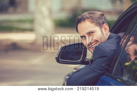 Closeup portrait happy smiling young man buyer sitting in his new car excited ready for trip isolated outside dealer dealership lot office. Personal transportation auto purchase concept