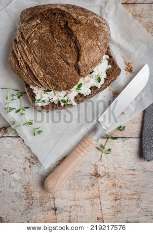 Homemade farm bread with cottage cheese curd and thyme herb malt flour and curd cream in bowl on wooden table.