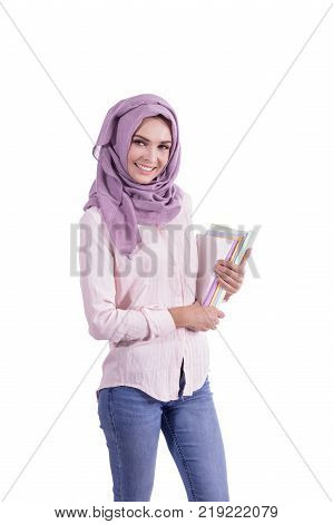 portrait of beautiful college student wearing hijab smiling while bringing some books isolated on white background