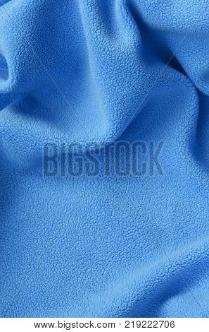 The blanket of furry blue fleece fabric. A background of light blue soft plush fleece material with a lot of relief folds