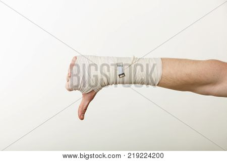 Bad news and information. Medicine aspects. Male hand with bandage showing thumb down sign symbol.