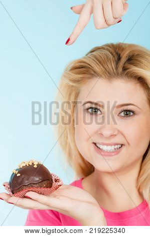 Diet sweets food concept. Woman holding delicious chocolate cupcake with peanut frosting about to take bite