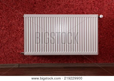 white heating radiator under in red room