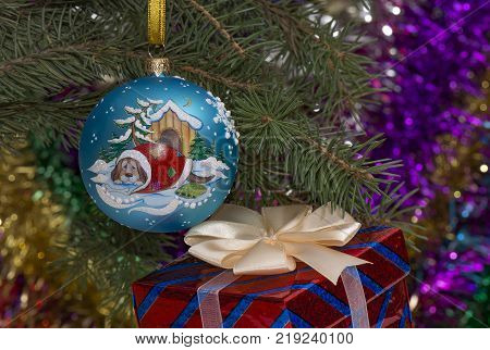 Christmas ball with the dog kennels on the spruce branch with beads and gift box.