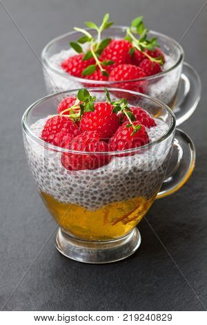 Chia seed pudding with orange marmalade and fresh raspberries on black stone background