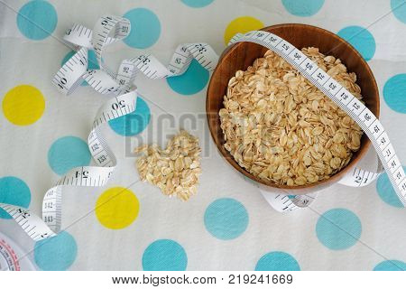 Rolled oats in a wooden bowl with tape measure