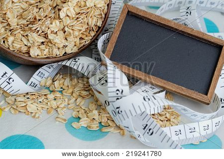 Mini blackboard for text space with tape measure and full bowl of rolled oat