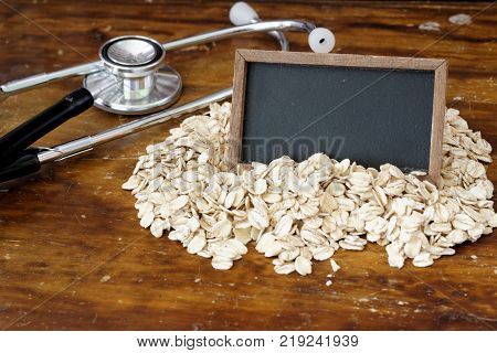 Fitness and healthcare concept with stethoscope, oat and blank small blackboard. Copy space.