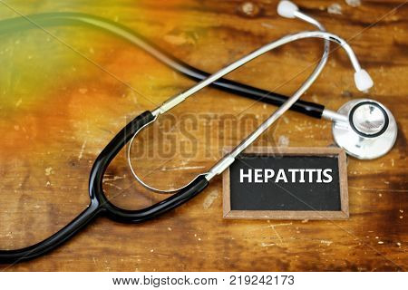 Word HEPATITIS written on mini blackboard with stethoscope on wooden table