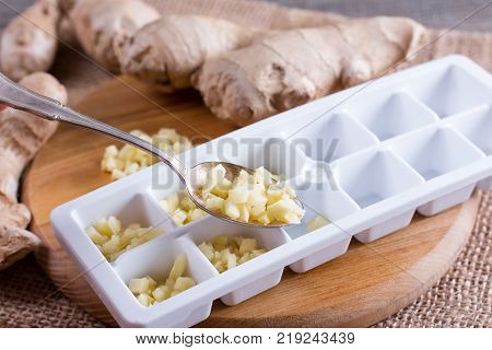 Pieces of ginger in a container for freezing ice cubes on a board
