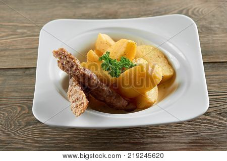 Little restaurant bowl served with goldy fried potato slices, thin sausage and decorated with parsley leaves. Looks very delicious and nourisihing.