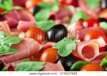 Close shot of delicious restaurant appetizer : canapees with white bread, bacon rolls, fresh cherry tomatoes and green parsley leaves. Tasty snack for catering or buffet.