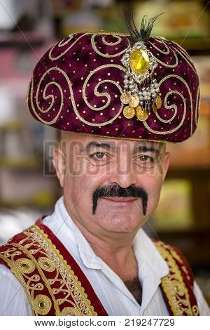 KEMER TURKEY - OCTOBER 18 2017 : Editorial photo . Portrait of a Turkish man dressed in national clothes which sells oriental sweets at a local bazaar in Kemer. Close up