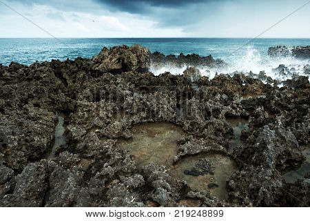 Waves break on rocky shore. Tourist beach resort in Nuca Dua of Bali