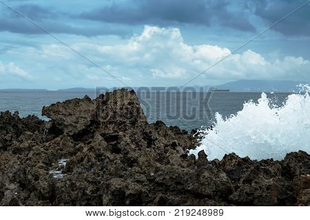 Waves break on rocky shore. Tourist beach resort in Nuca Dua of Bali