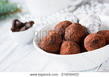 Raw vegan chocolate truffles made with dates and raw chocolate in white bowl. Horizontal view, closeup