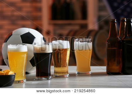 Glasses with different sorts of beer on table in football bar