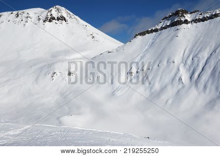 Snowy off-piste with traces of skis snowboards and avalanches. Caucasus Mountains in sun winter day Georgia region Gudauri.