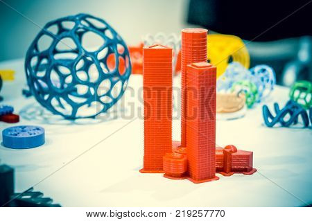 Abstract object of a red color printed on a 3d printer on a white table. Fused deposition modeling, FDM. Progressive modern additive technology. Concept of 4.0 industrial revolution