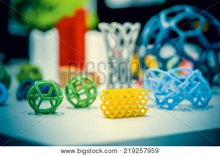 Many abstract models bright colorful objects printed on a 3d printer on a white table. Fused deposition modeling, FDM. Progressive modern additive technology. Concept of 4.0 industrial revolution
