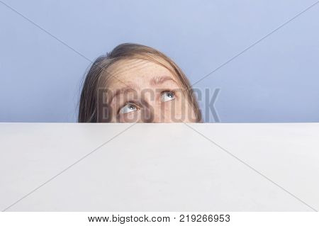 Top of female face behind white banner, isolated on blue background