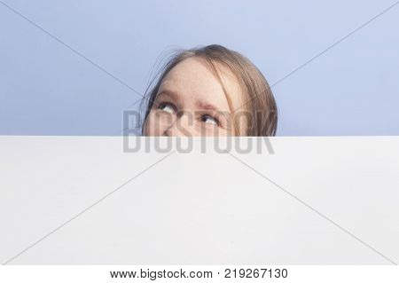 Top of female face behind white banner, isolated on blue background