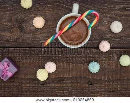 Freshly brewed cocoa and colorful biseza with candy on an old wooden table