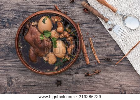 Eggs and pork in brown sauce frogs with herb and egg on wooden table Egg spoon Thai food khai phalo