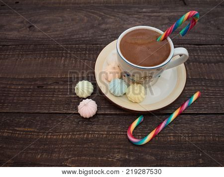 Freshly brewed cocoa and colorful biseza with candy on an old wooden table