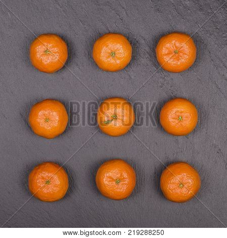 Fresh orange tangerine fruit mandarin pattern high vitamin C good for health top view on a black slate background close up