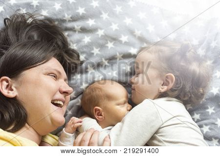 mother with two children lying on the bed and enjoying spending time with them