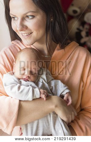 a young mother enjoys the first days of motherhood with her child holding it in her arms
