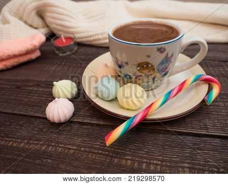 Freshly brewed cocoa and colorful biseza with candy on an old wooden table