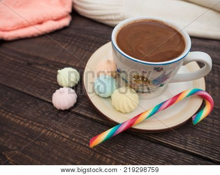 Freshly brewed cocoa and colorful biseza with candy on an old wooden table