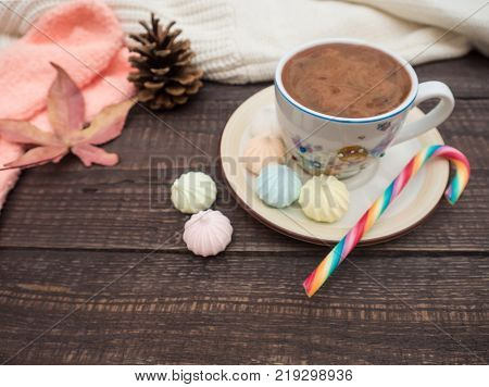 Freshly brewed cocoa and colorful biseza with candy on an old wooden table