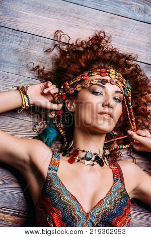 Beautiful bright woman with curly foxy hair wears a dress and beads in boho style. Ethnic style in clothes.