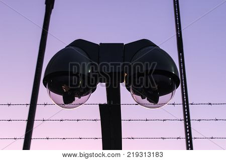surveillance camera and barbed wire during sunset