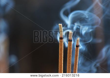 three incense sticks burning and smoking during ceremony