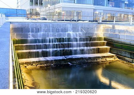 Water cascading down tiers in tidal well along Harborwalk in South Boston
