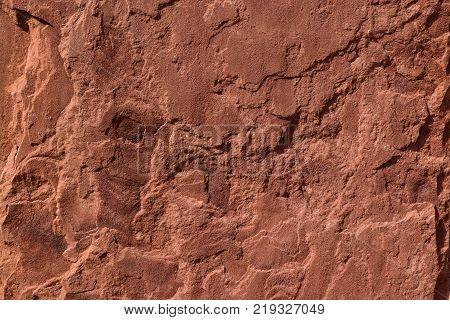 red sand stone texture pattern on surface of the wall. flaking red sandstone rock surface with topographic texture.